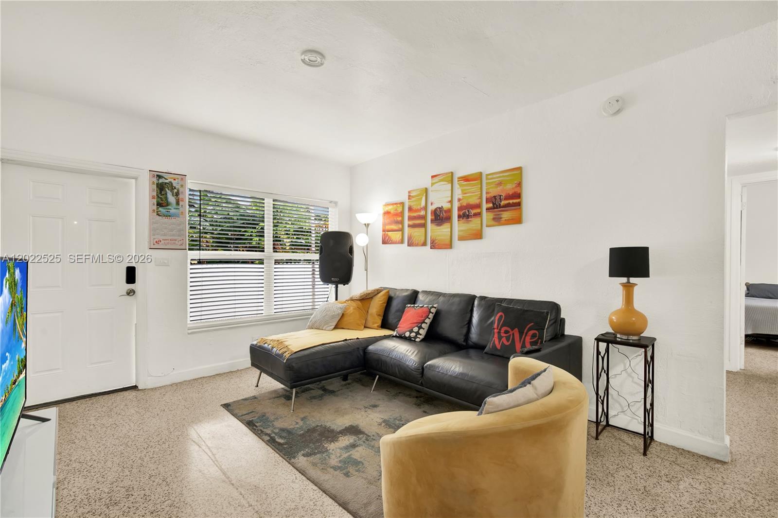 A living room features a black sectional sofa, a yellow armchair, and wall art — 1236 NE 109th St # 2, Miami FL 33161, MIAMI, FL