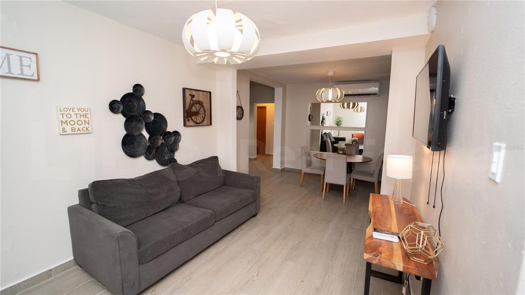 A living room with a gray sofa, wood-look tile flooring, and an adjacent dining area — 2058 ESPAÑA STREET, SAN JUAN, PR