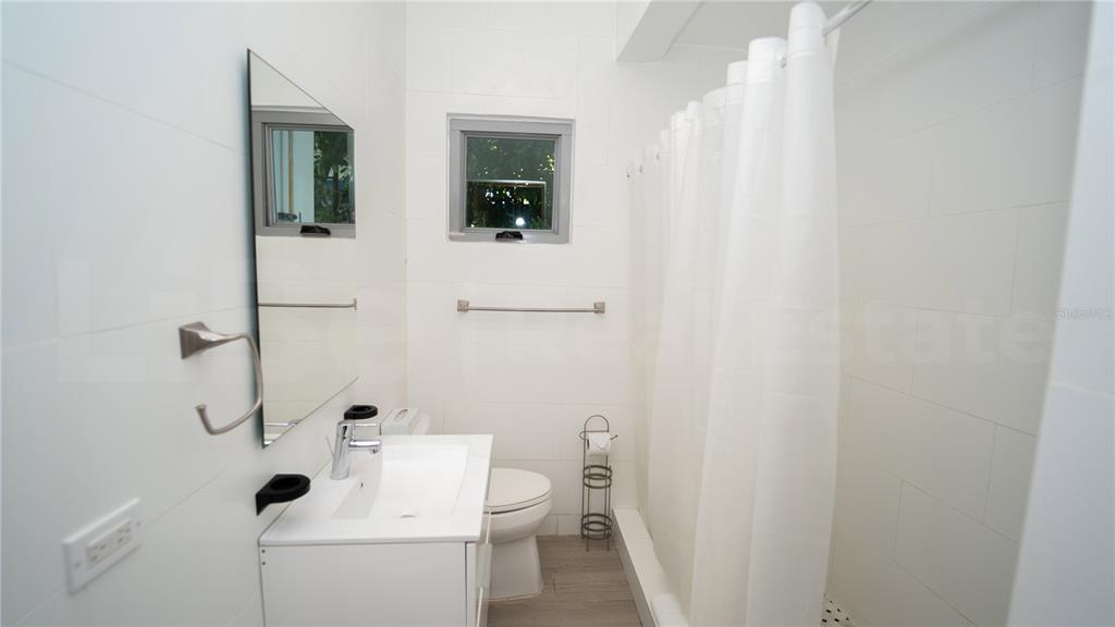 A bathroom features white tiled walls, a vanity with a mirror, and a shower curtain — 2058 ESPAÑA STREET, SAN JUAN, PR