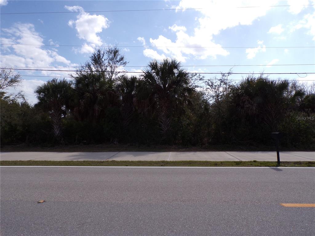A paved road and sidewalk front a wooded lot with several palm trees — 14589 KEYSTONE BOULEVARD, PORT CHARLOTTE, FL