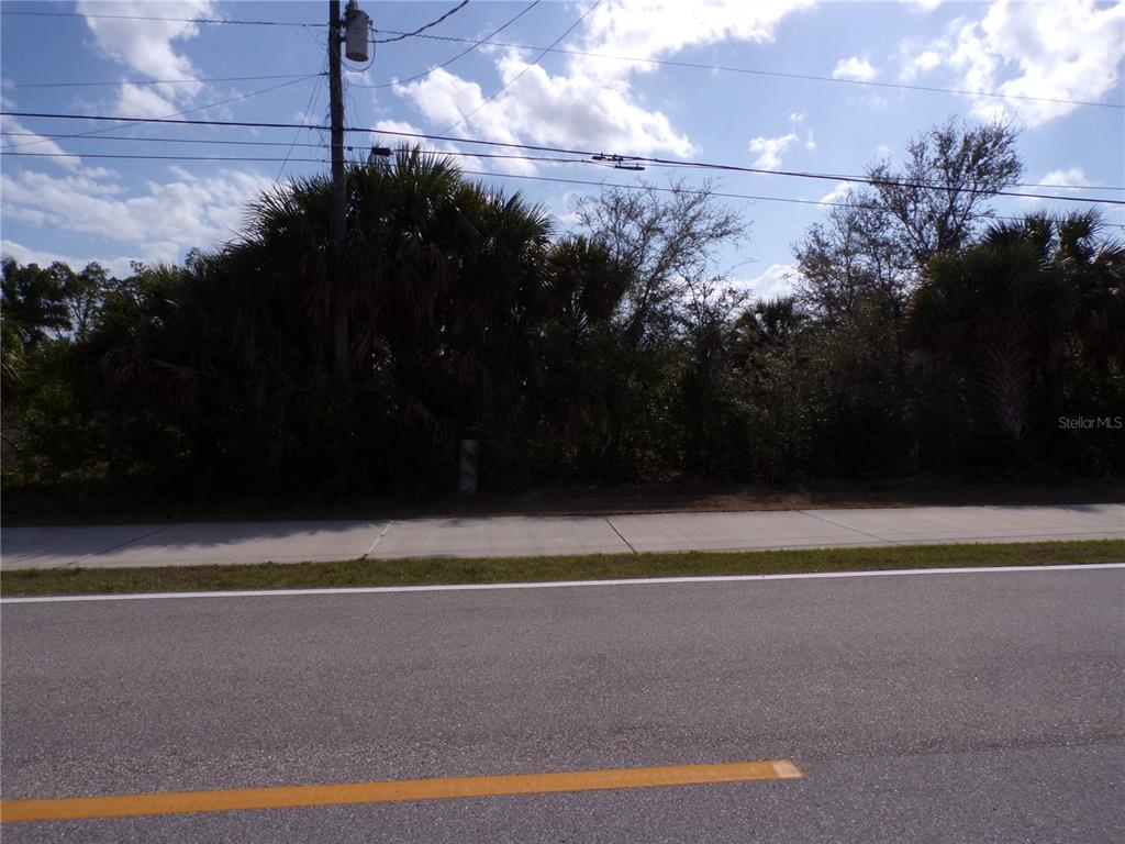 A paved road and sidewalk front a vacant, wooded lot with a utility pole — 14589 KEYSTONE BOULEVARD, PORT CHARLOTTE, FL