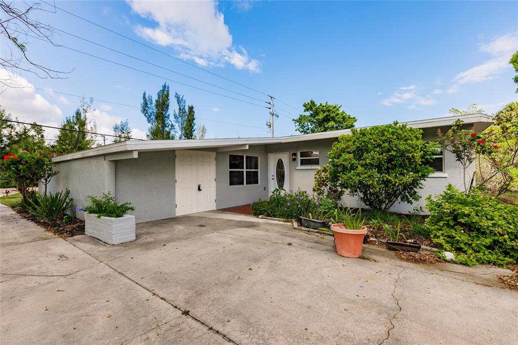 A single-story gray house with a concrete driveway, a carport, and front yard landscaping — 3129 BUTTONWOOD PLACE, PUNTA GORDA, FL