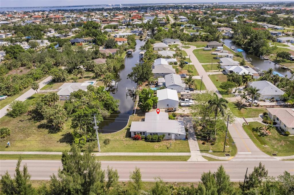 An aerial view shows a single-story house with a canal in a residential neighborhood — 3129 BUTTONWOOD PLACE, PUNTA GORDA, FL