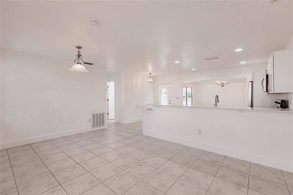 A bright, tiled dining area opens to a kitchen with a white breakfast bar — 3129 BUTTONWOOD PLACE, PUNTA GORDA, FL