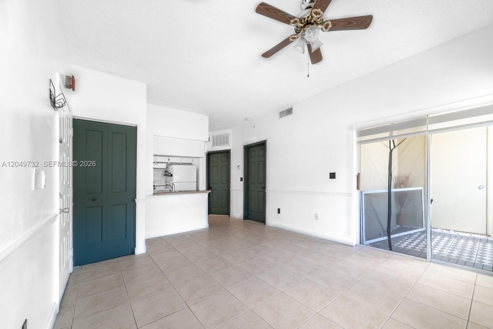 An interior view shows a tiled living area with a ceiling fan and sliding glass doors — 18308 NW 68th Ave # B, Hialeah FL 33015, HIALEAH, FL