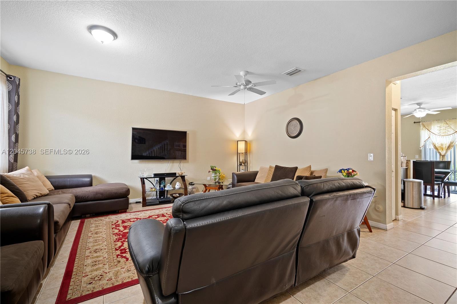 A living room features brown leather sofas, a wall-mounted television, and a red area rug — 8915 SW 19th St, Miramar FL 33025, MIRAMAR, FL
