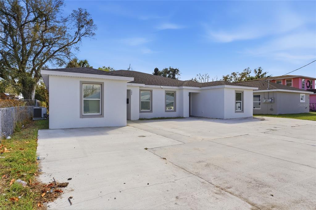A single-story white house with a large concrete driveway and a gray shingled roof — 302 AVENUE P NW, WINTER HAVEN, FL