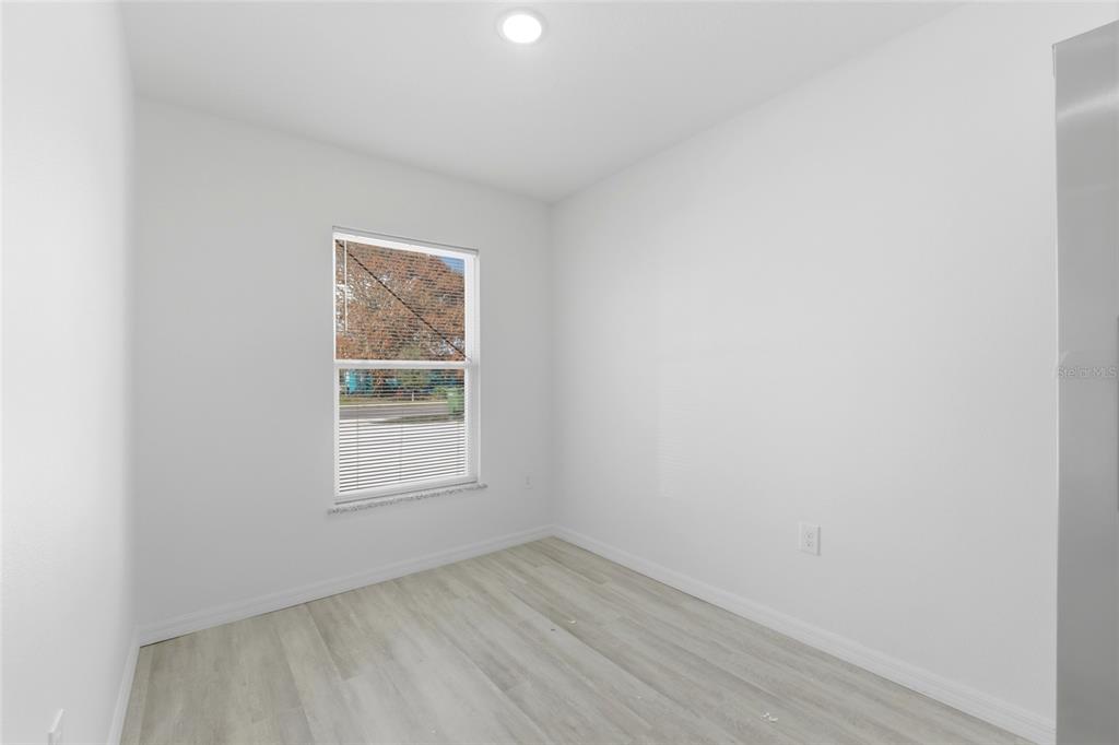 An empty room with white walls, light wood-look flooring, and a single window — 302 AVENUE P NW, WINTER HAVEN, FL