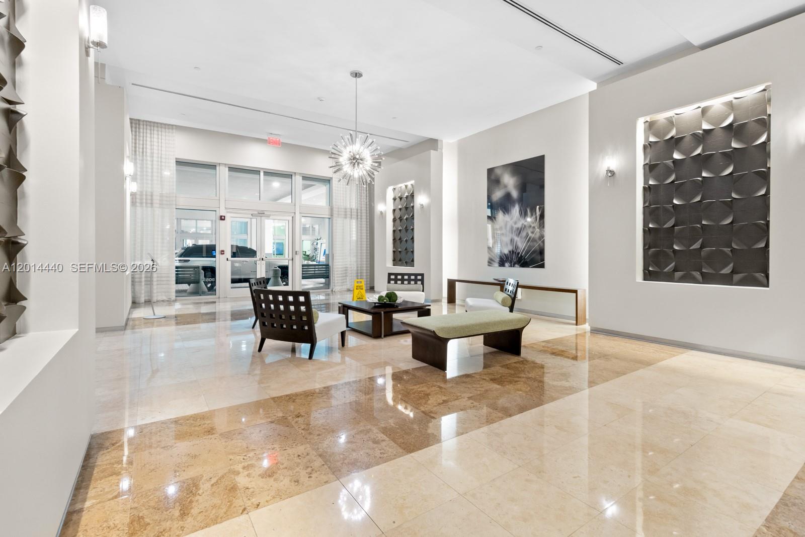 A modern building lobby features marble floors, a central chandelier, and contemporary seating areas — 9055 SW 73rd Ct # 1506, Miami FL 33156, MIAMI, FL