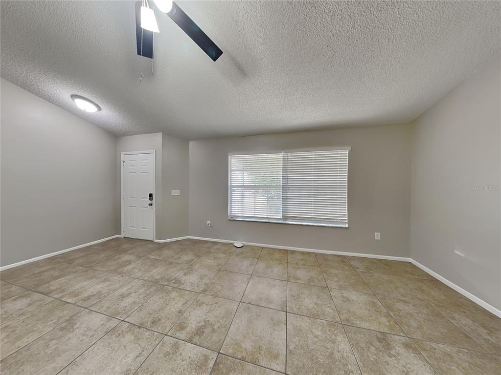 An empty room with beige tile flooring, light gray walls, and a ceiling fan — 1488 COUNTRY MANSION COURT, APOPKA, FL