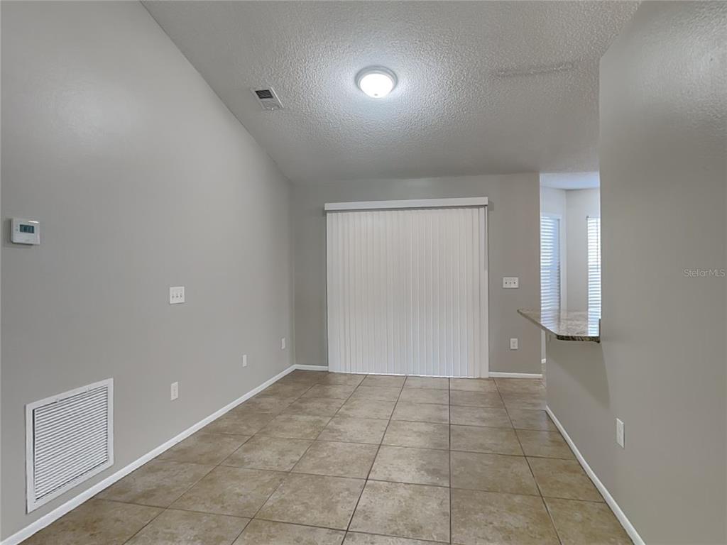 An empty dining room with light gray walls, tile flooring, and a sliding glass door — 1488 COUNTRY MANSION COURT, APOPKA, FL
