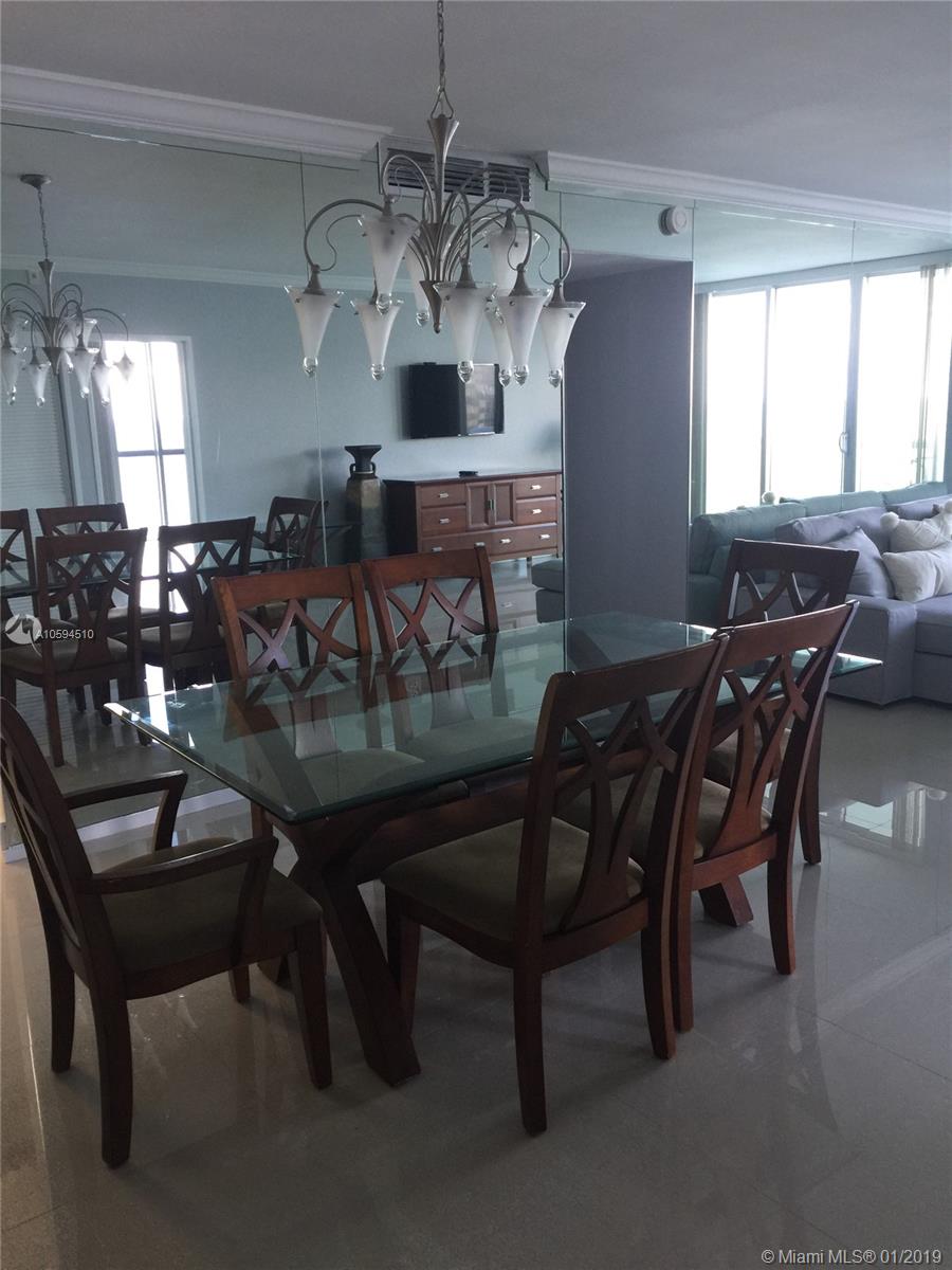 A dining room features a glass-topped table, wooden chairs, and a mirrored wall — 3901 S Ocean Dr # 14E, Hollywood FL 33019, HOLLYWOOD, FL