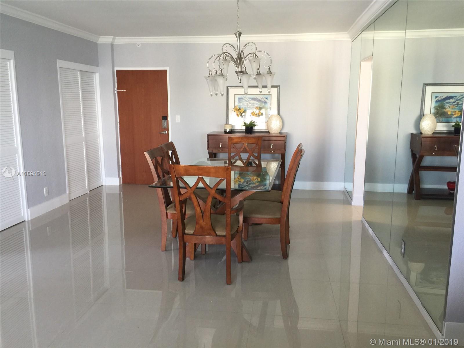 A dining room features a glass-topped table, wooden chairs, a chandelier, and mirrored walls — 3901 S Ocean Dr # 14E, Hollywood FL 33019, HOLLYWOOD, FL