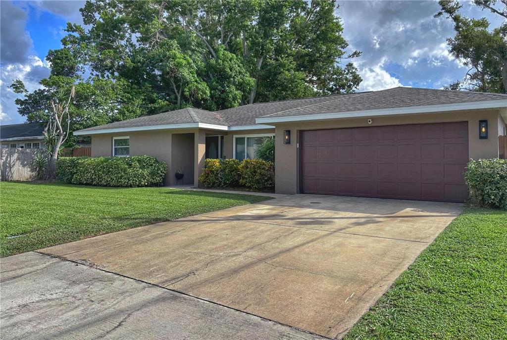 A single-story house with a brown garage door, concrete driveway, and green landscaping — 4033 W 13, BRADENTON, FL