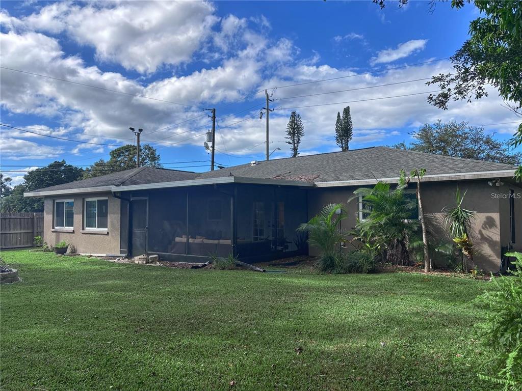 The exterior of a house features a screened-in porch and a large grassy backyard — 4033 W 13, BRADENTON, FL