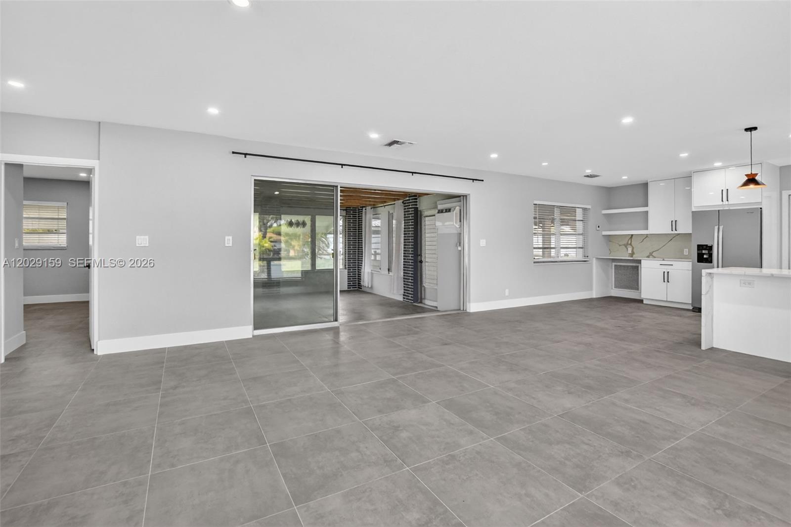 An open-concept living area features gray tile flooring, recessed lighting, and an adjacent modern kitchen — 1320 SE 10th St, Deerfield Beach FL 33441, DEERFIELD BEACH, FL