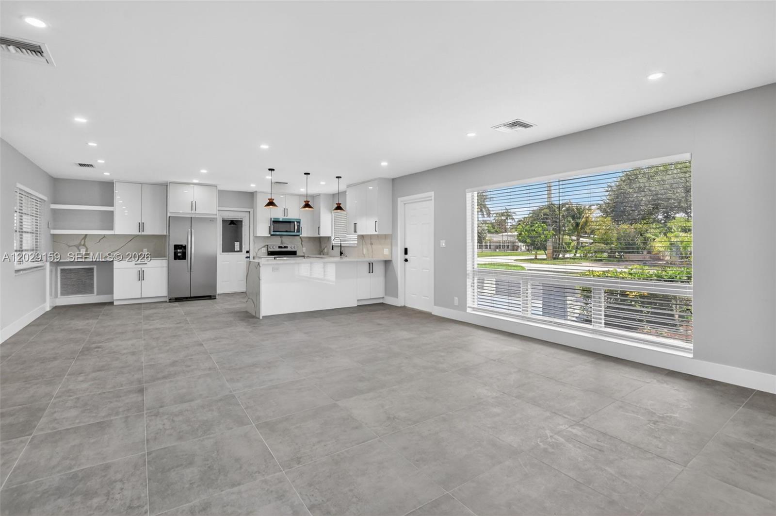 A modern kitchen with white cabinets and a large window overlooks a residential street — 1320 SE 10th St, Deerfield Beach FL 33441, DEERFIELD BEACH, FL