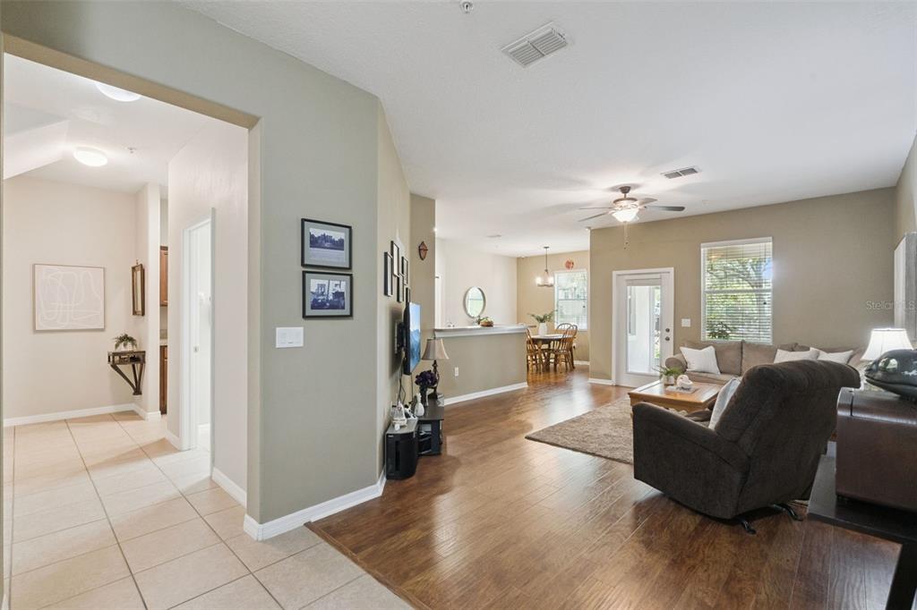 An open-concept living room and dining area with hardwood floors, a ceiling fan, and furniture — 15514 CAMPDEN STREET, WINTER GARDEN, FL