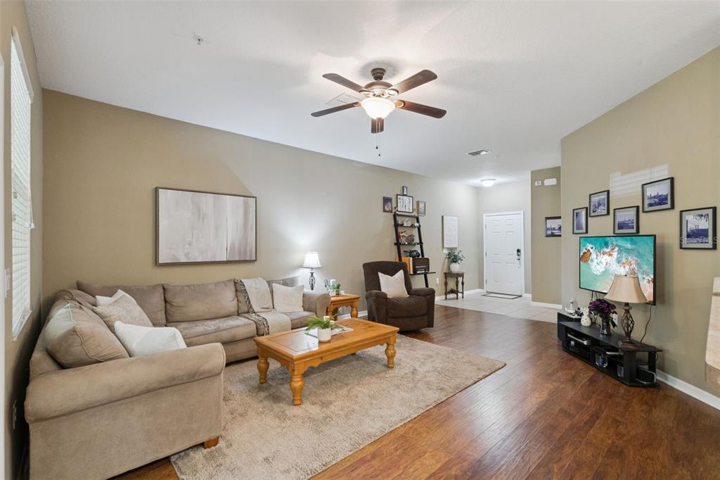 A living room features a sectional sofa, a wooden coffee table, and a wall-mounted television — 15514 CAMPDEN STREET, WINTER GARDEN, FL