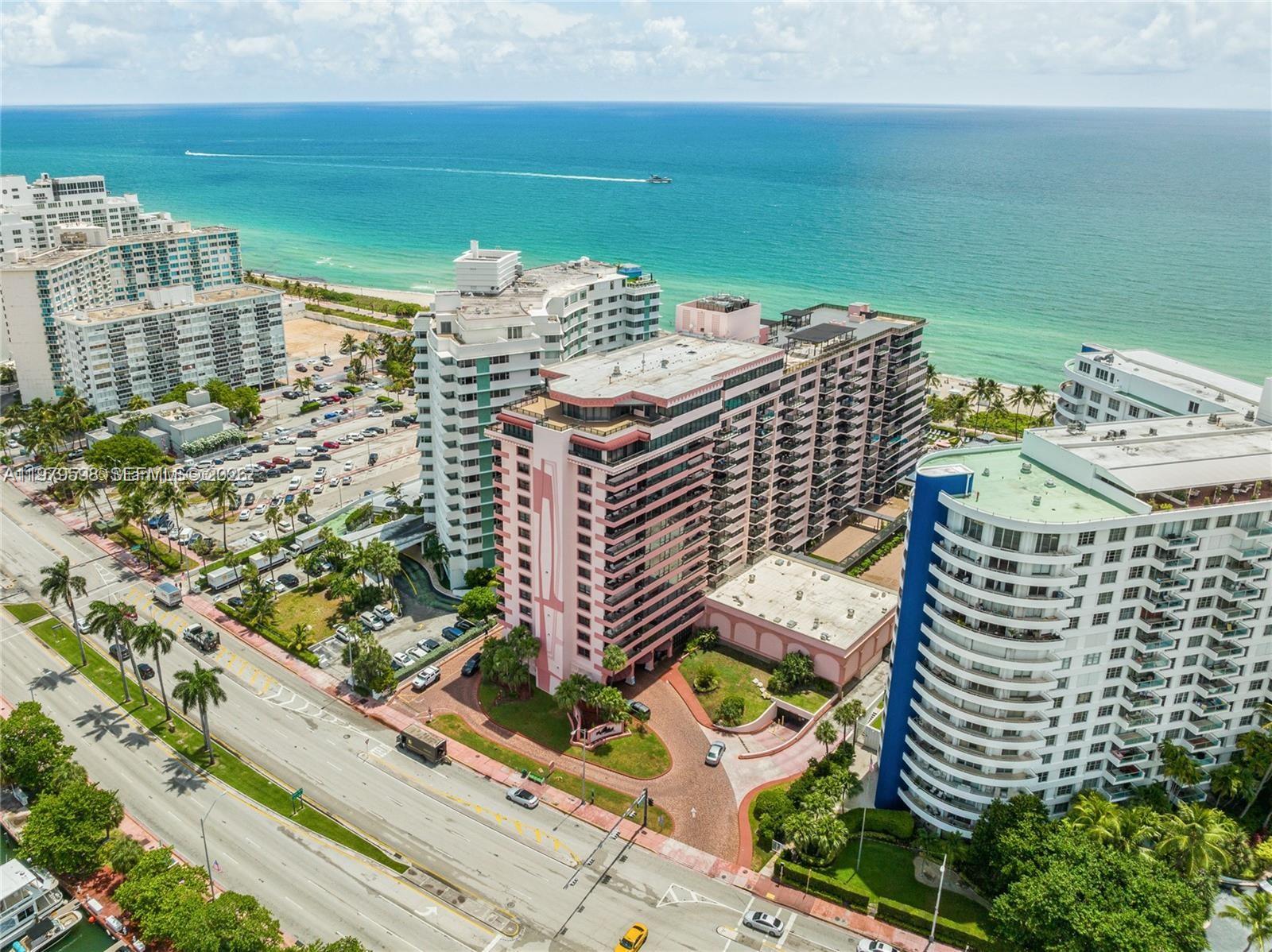 An aerial view shows a resort-style pool complex with rock features and palm trees — 5225 Collins Ave # 1214, Miami Beach FL 33140, MIAMI BEACH, FL