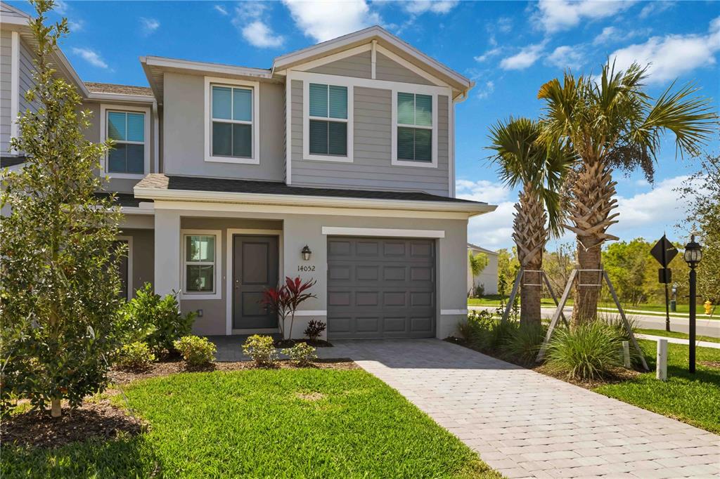 A two-story townhouse features a gray exterior, a single-car garage, and a paved driveway — 14052 LILAC SKY TERRACE, BRADENTON, FL
