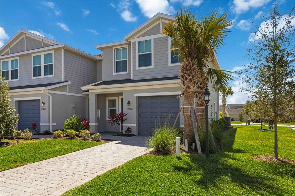 A two-story gray townhouse with a paved walkway, a single-car garage, and a palm tree — 14052 LILAC SKY TERRACE, BRADENTON, FL