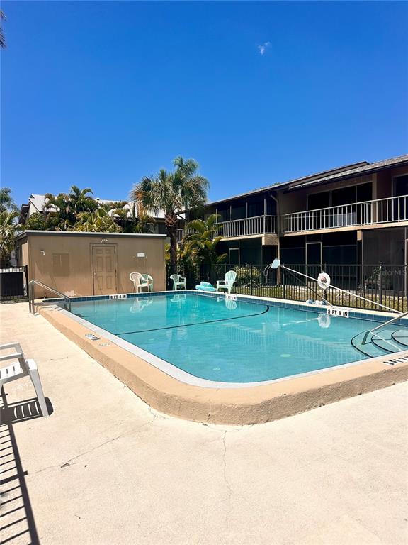 An outdoor swimming pool is surrounded by a concrete deck and a multi-story apartment building — 2948 CLARK BOULEVARD UNIT 224, SARASOTA, FL