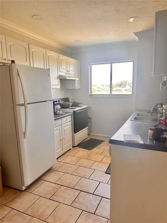 A kitchen features white cabinets, a white refrigerator, a stove, and tiled flooring — 2948 CLARK BOULEVARD UNIT 224, SARASOTA, FL