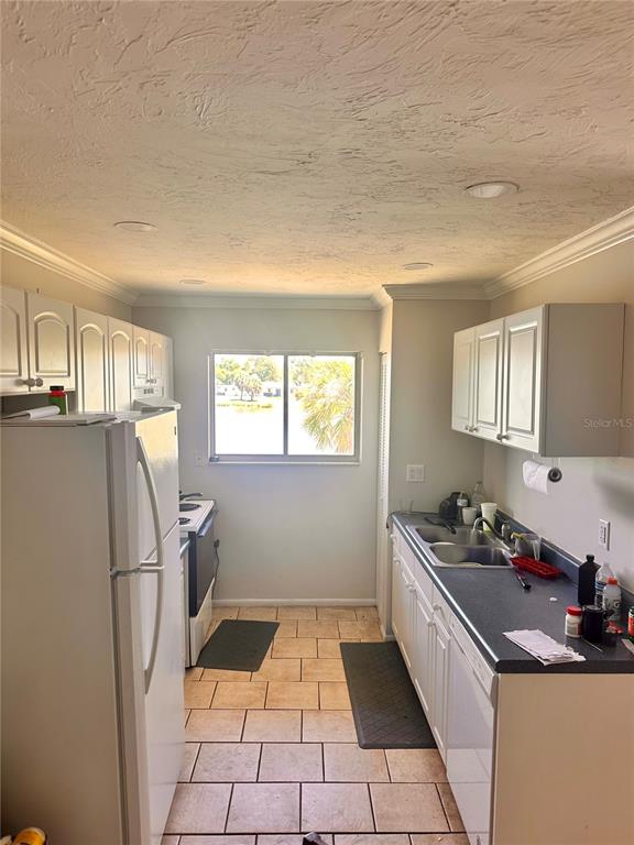 A kitchen with white cabinets, a white refrigerator, a dark countertop, and tiled flooring — 2948 CLARK BOULEVARD UNIT 224, SARASOTA, FL