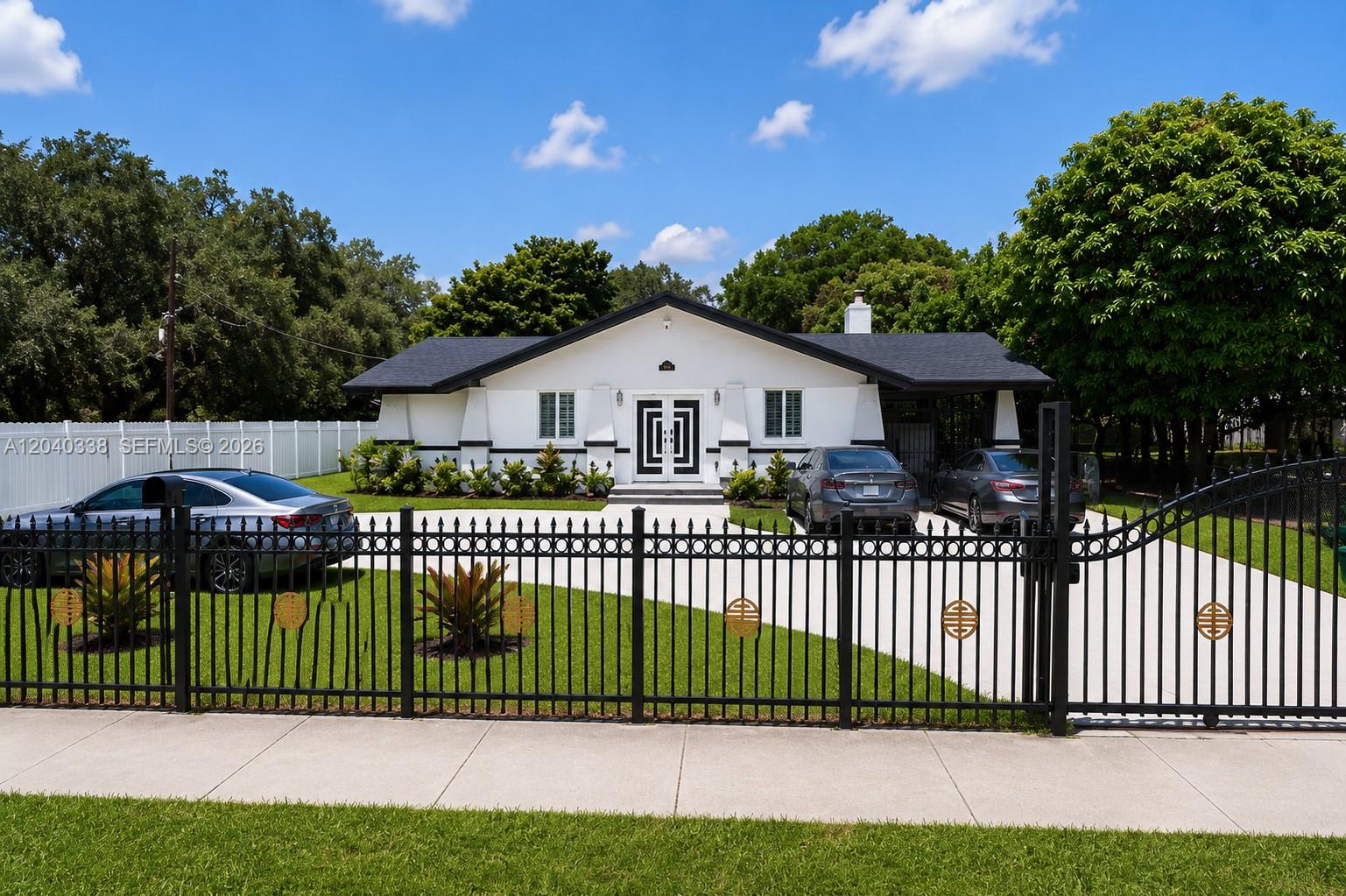 A white single-story house with a black roof sits behind a black metal fence — 1860 NW 81st St, Miami FL 33147, MIAMI, FL