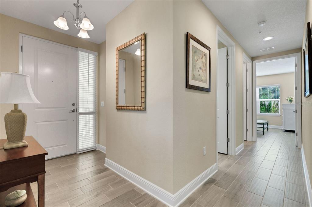An entryway features a white front door, a wall mirror, and light-colored tile flooring — 3450 77TH STREET W UNIT 201, BRADENTON, FL