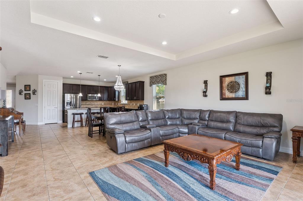 A spacious open-concept living room features a large gray sectional sofa and a kitchen area — 2651 MEAD AVENUE, ST CLOUD, FL