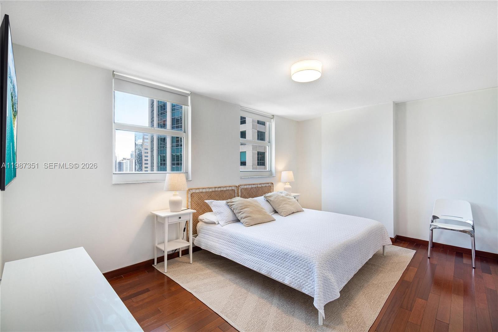 A bedroom features a queen bed, two windows with city views, and dark wood flooring — 1200 Brickell Bay Dr # 2824, Miami FL 33131, MIAMI, FL