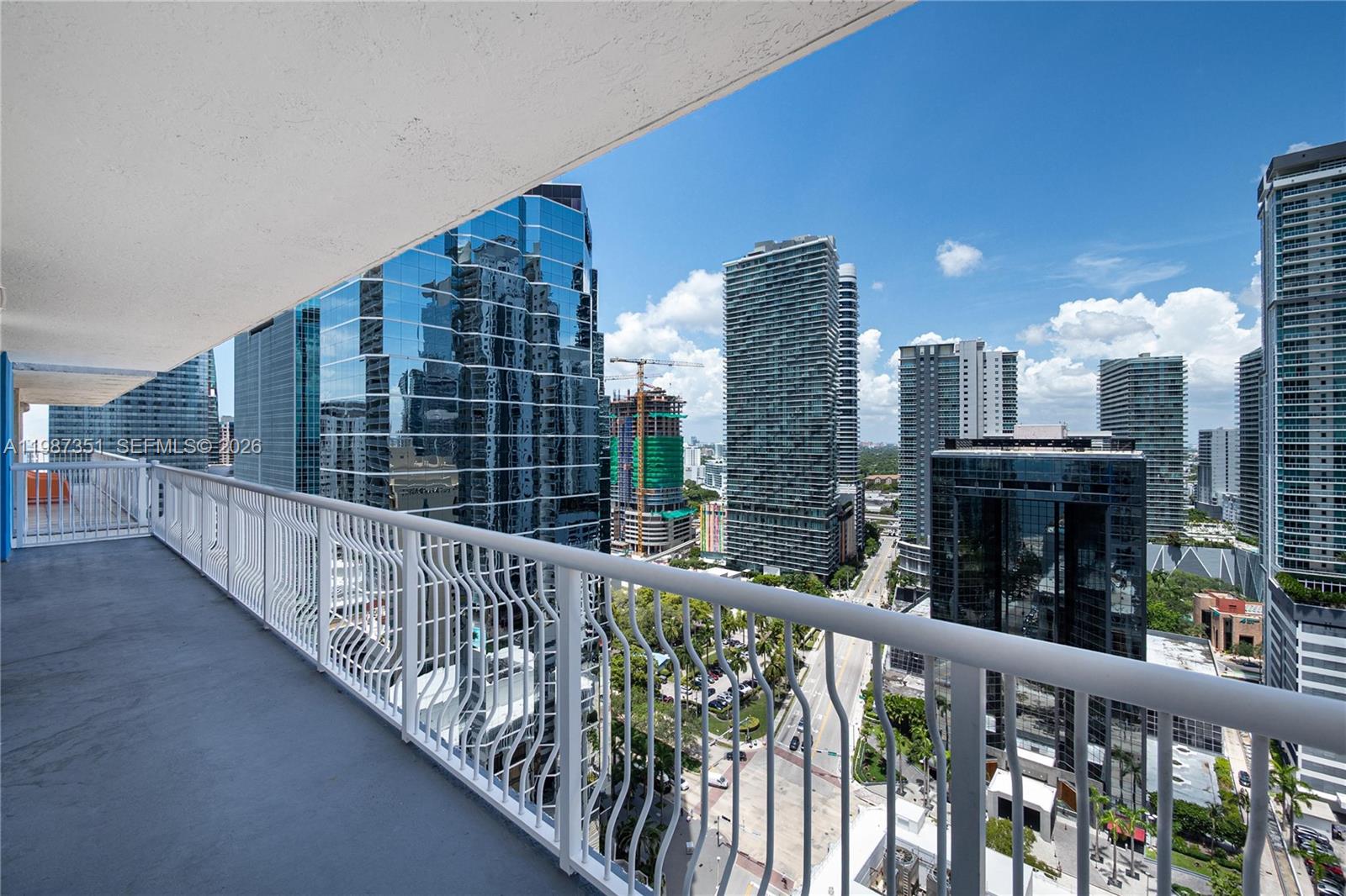 A high-rise balcony overlooks a dense urban cityscape with modern glass skyscrapers and a street — 1200 Brickell Bay Dr # 2824, Miami FL 33131, MIAMI, FL