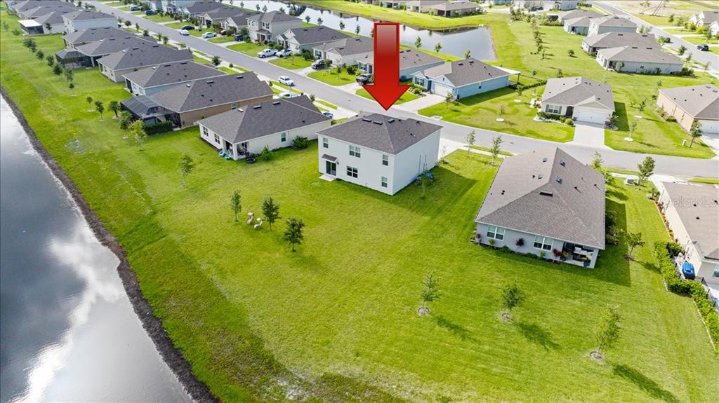 An aerial view shows a two-story suburban house with a large backyard near water — 1317 MIDDLE LAKE DRIVE, ORMOND BEACH, FL