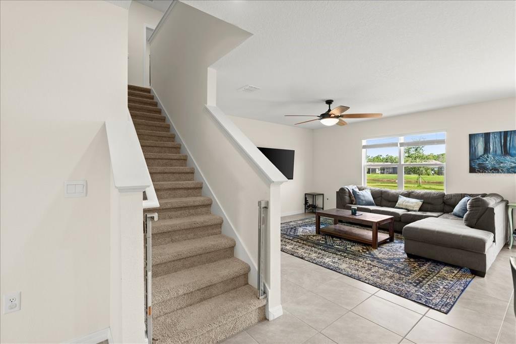 A carpeted staircase leads to an upper level next to a living room with tile — 1317 MIDDLE LAKE DRIVE, ORMOND BEACH, FL