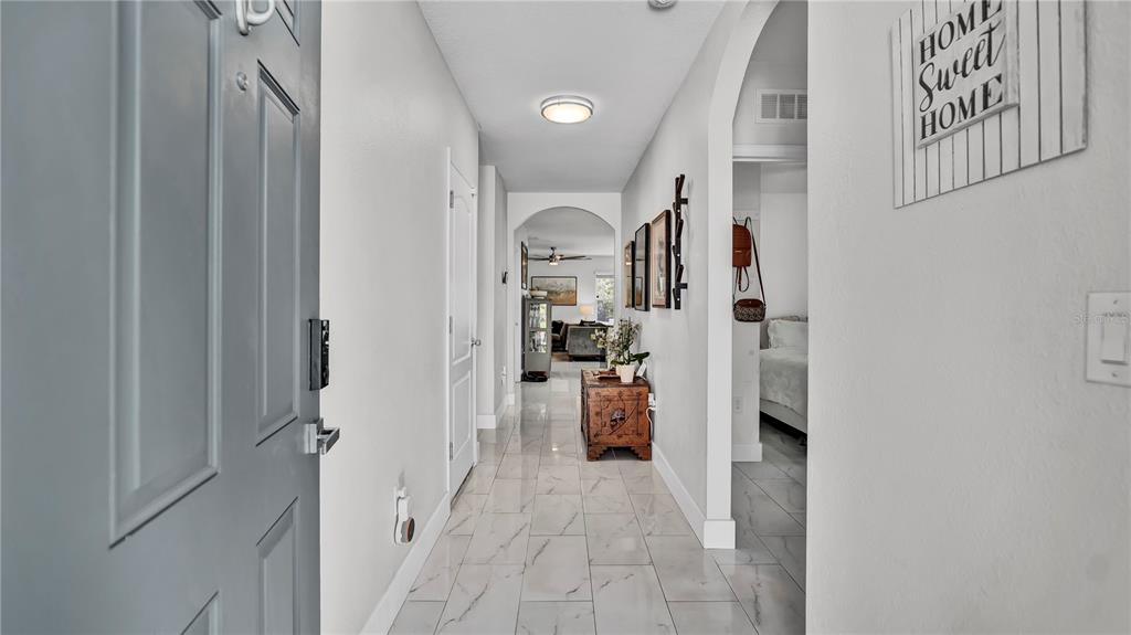 A tiled entryway hallway leads to an arched opening with a view of the living area — 1576 DIAMOND LOOP DRIVE, KISSIMMEE, FL