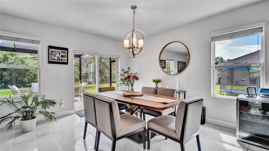 A dining room features a wooden table, upholstered chairs, a globe chandelier, and tile flooring — 1576 DIAMOND LOOP DRIVE, KISSIMMEE, FL