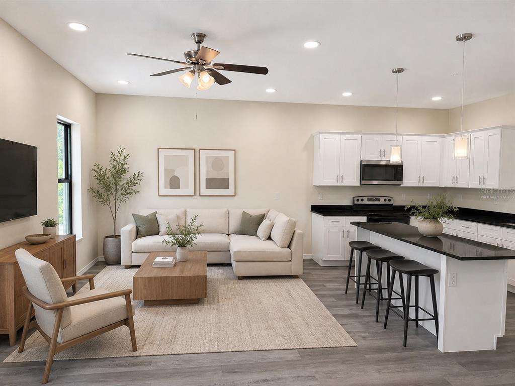 A living room with a sectional sofa, coffee table, and an open kitchen with island — 4349 CAMBIO GARDENS CT, TAMPA, FL