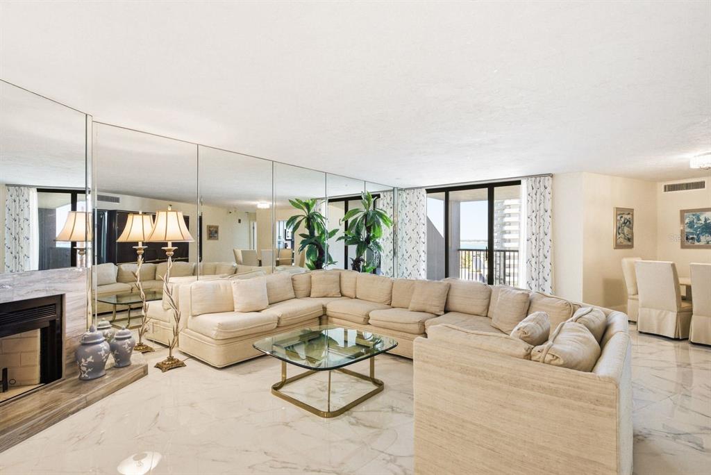 A living room features a large sectional sofa, a glass coffee table, and mirrored walls — 1600 GULF BOULEVARD UNIT 817, CLEARWATER BEACH, FL