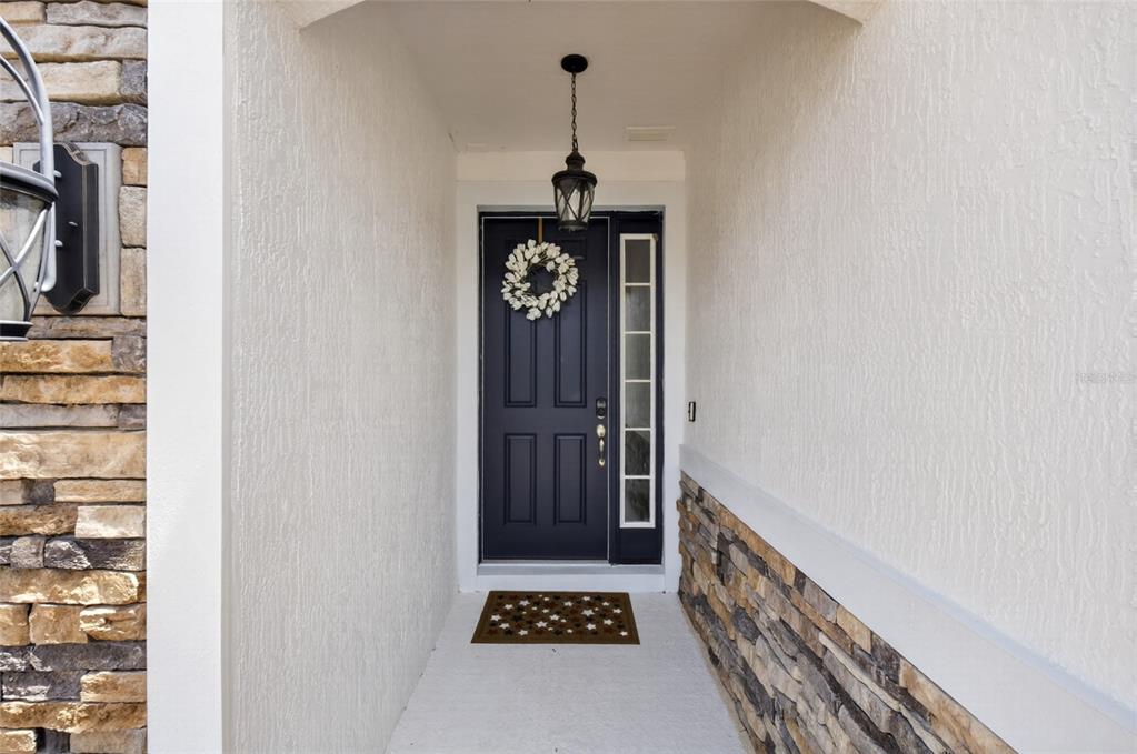 A front entryway features a dark blue door with a wreath and stone siding — 443 WRANGLER ROAD, WINTER GARDEN, FL