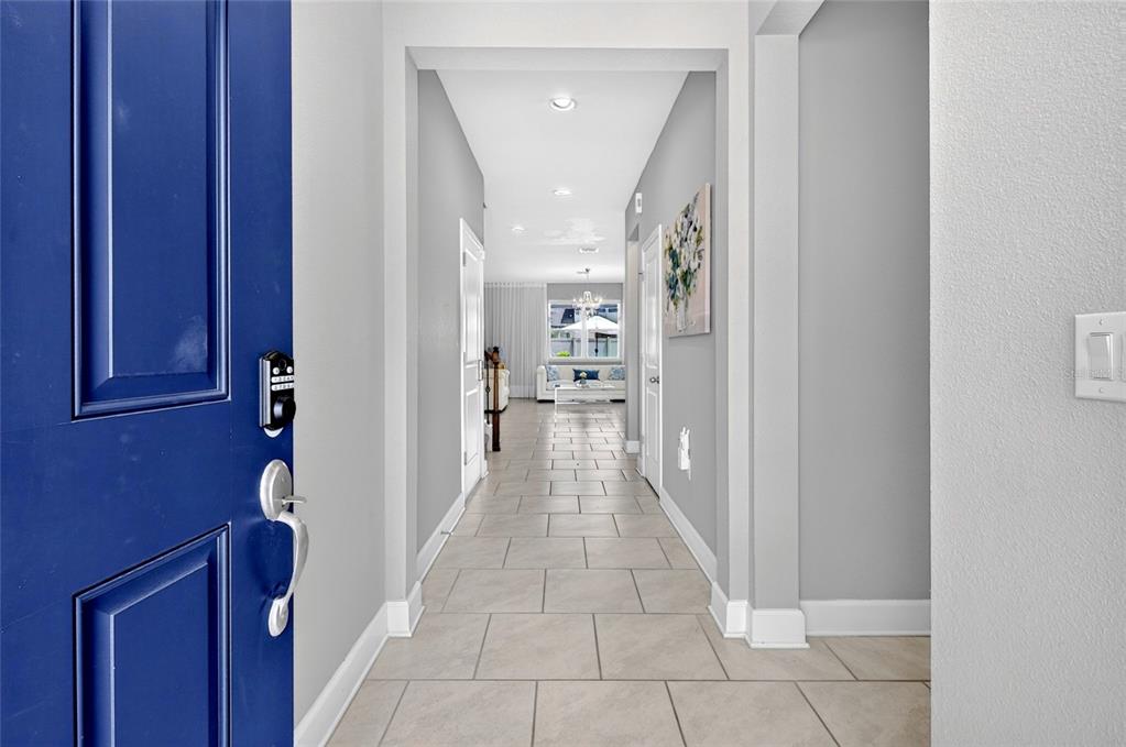 A view from an open blue front door looking down a tiled hallway toward a living room — 443 WRANGLER ROAD, WINTER GARDEN, FL