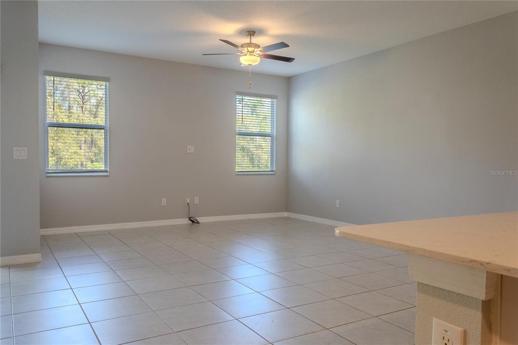 A spacious living room features light gray walls, tile flooring, and a ceiling fan — 17711 NECTAR FLUME DRIVE, LAND O LAKES, FL