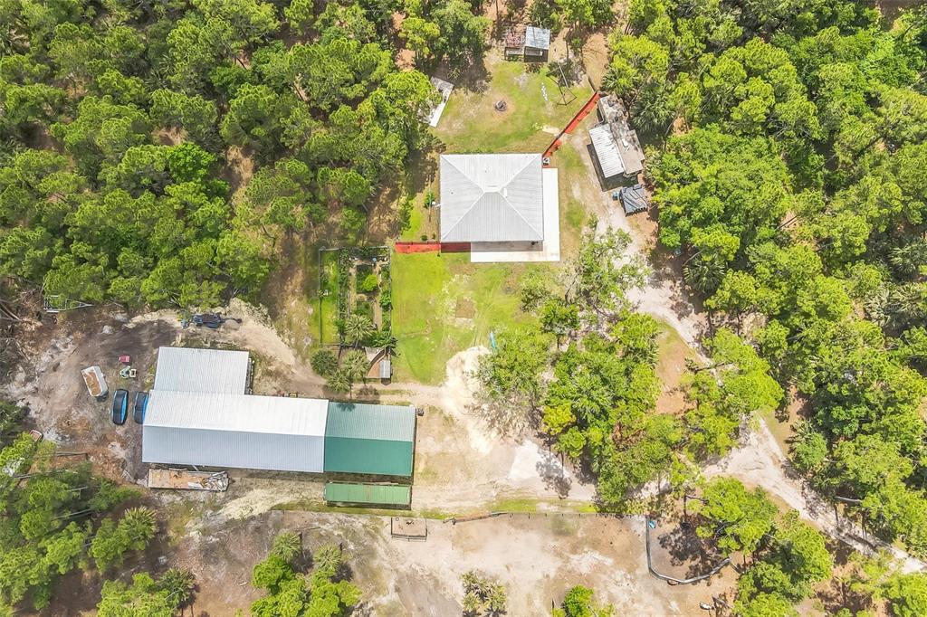 An aerial view shows a house, a large workshop, and outbuildings surrounded by dense forest — 723 RIVER RUN ROAD, OSTEEN, FL