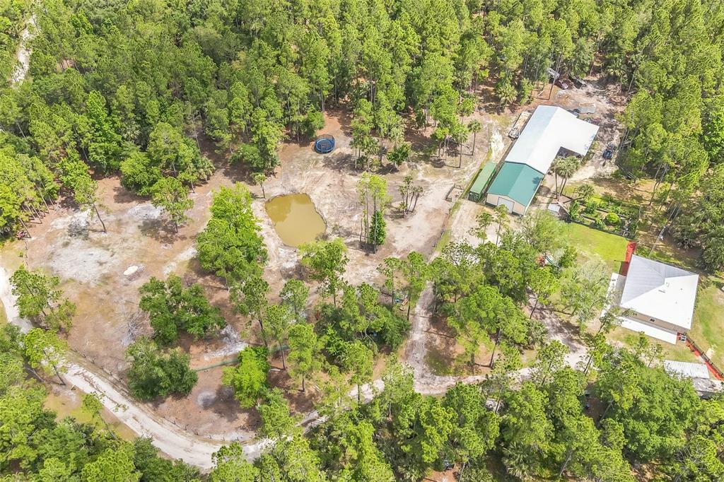 An aerial view shows a rural property with two buildings, a pond, and surrounding woods — 723 RIVER RUN ROAD, OSTEEN, FL