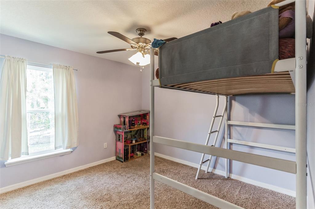 A bedroom with light purple walls, beige carpet, a ceiling fan, and a metal bunk bed — 723 RIVER RUN ROAD, OSTEEN, FL