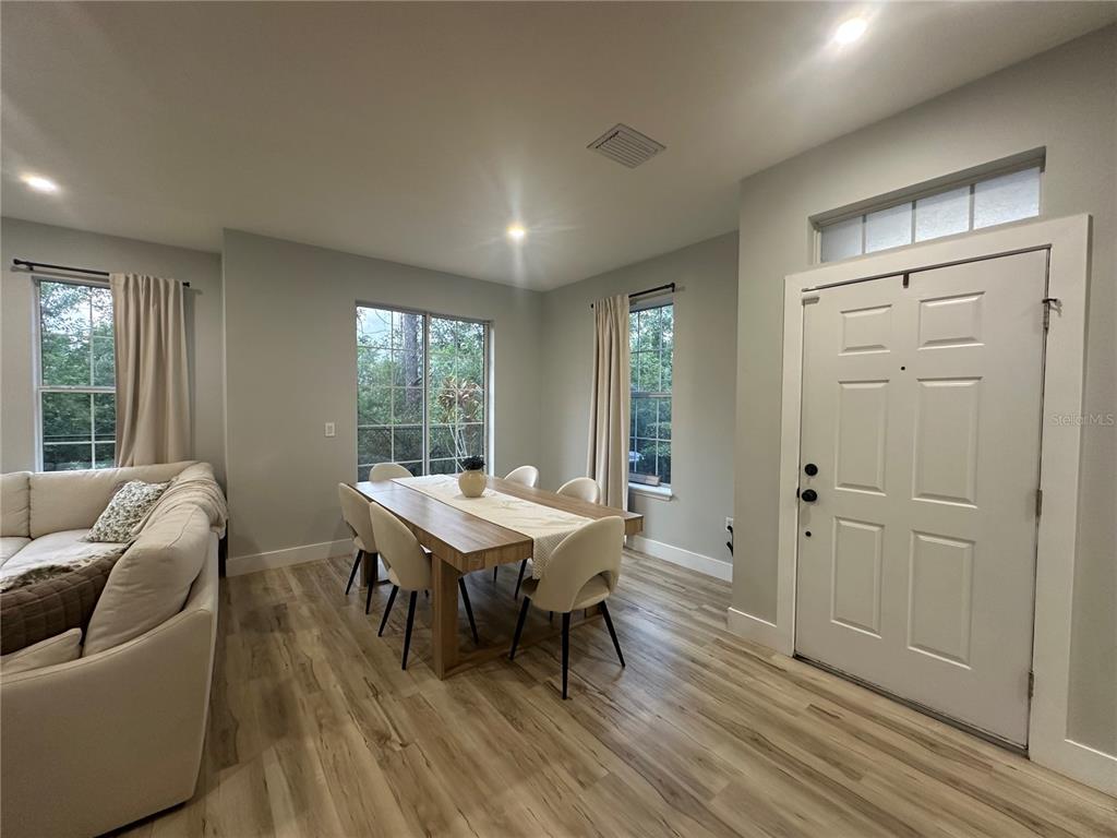 A dining area with a wooden table, light-colored chairs, and a white front door — 7544 RED MILL CIRCLE, NEW PORT RICHEY, FL