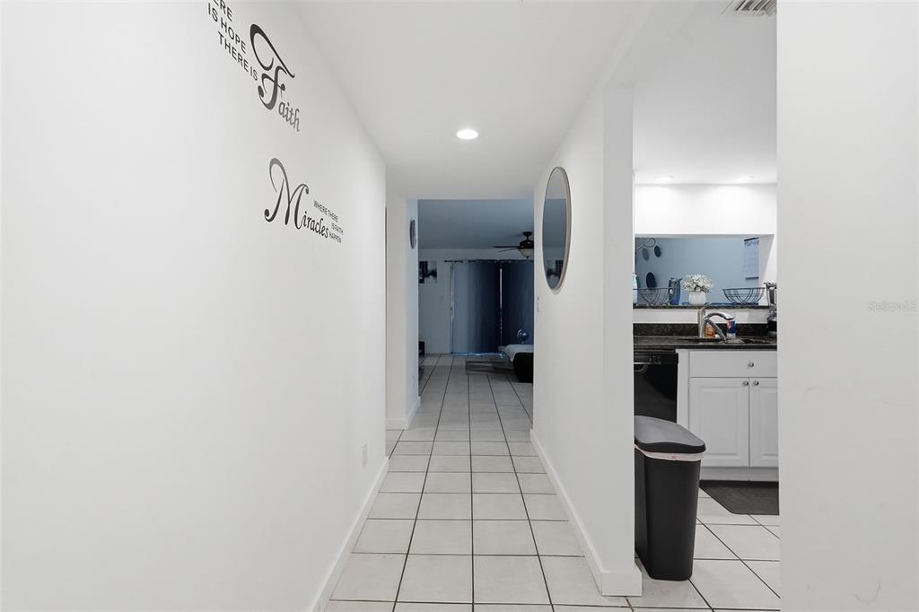 A hallway with white tile floors leads from a kitchen area toward a living space — 6340 NEWTOWN CIRCLE UNIT 40A2, TAMPA, FL