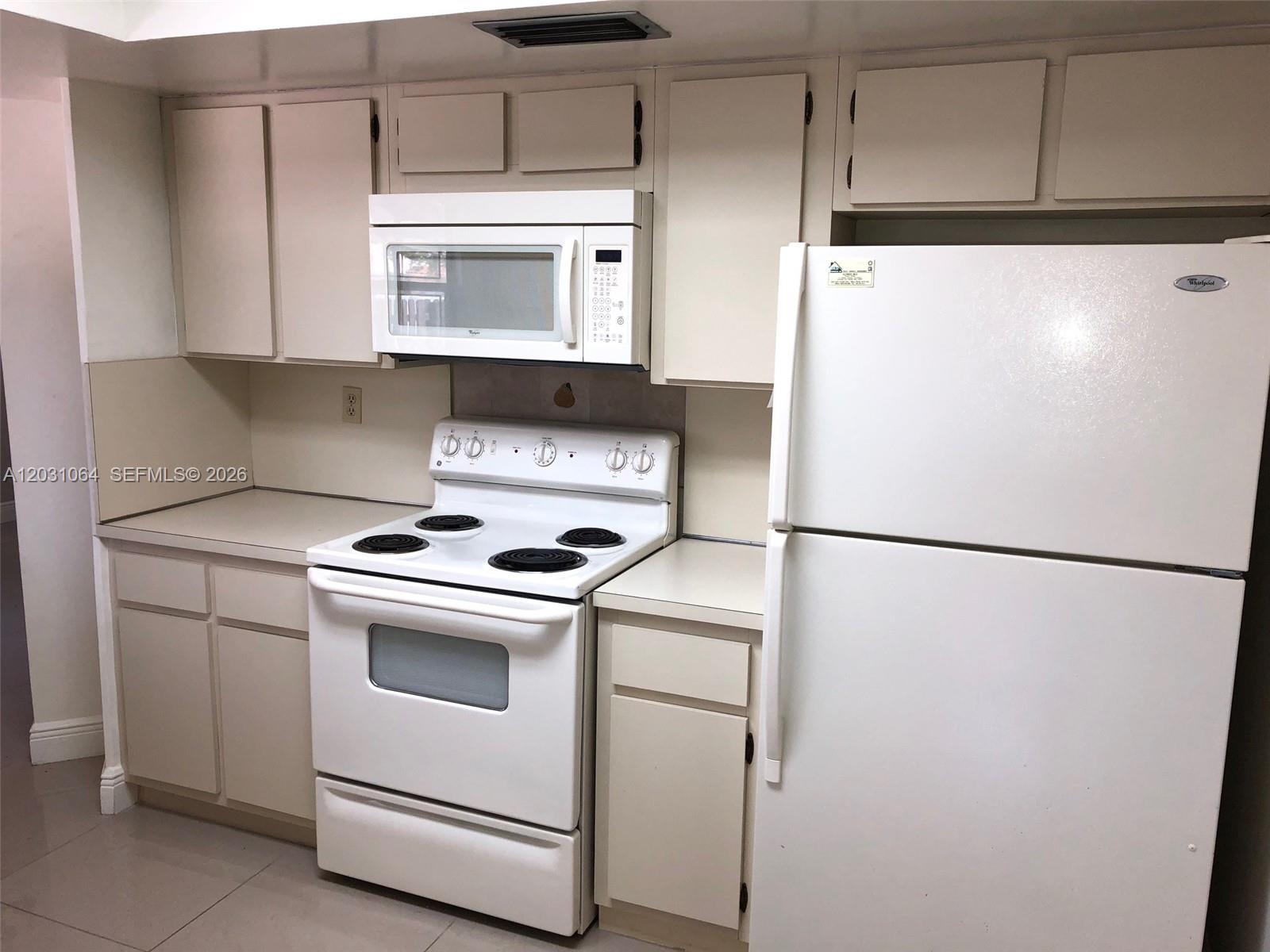 A kitchen features white appliances, beige cabinets, and light-colored countertops — 9082 SW 112 PL, Miami FL 33176, MIAMI, FL