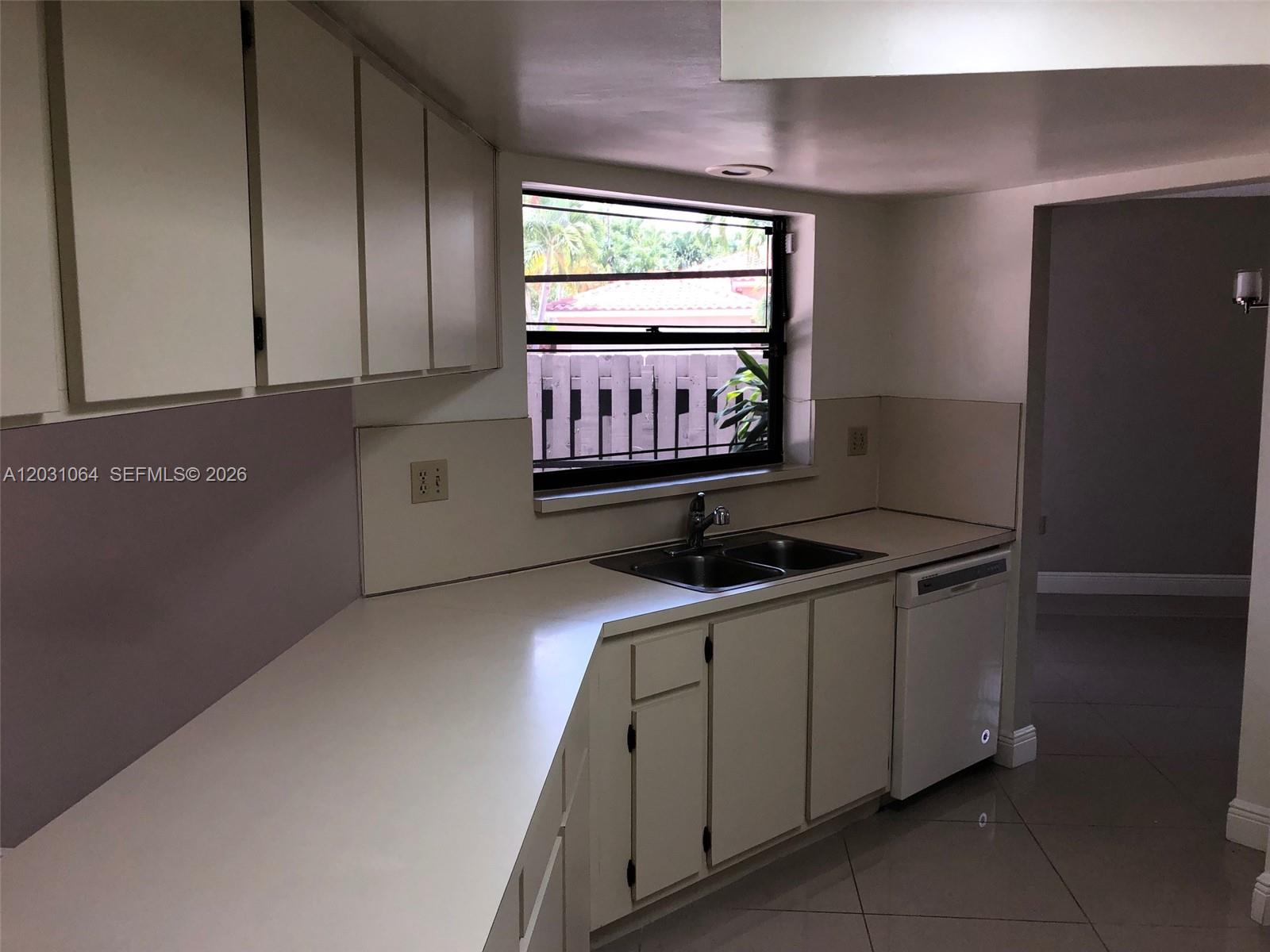 A kitchen features white cabinets, a double sink, a dishwasher, and a window view — 9082 SW 112 PL, Miami FL 33176, MIAMI, FL